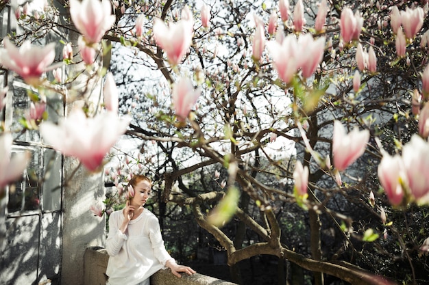 Free photo pretty girl at a spring photoshoot with magnolia