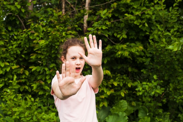 Free Photo pretty girl standing in park showing stop sign