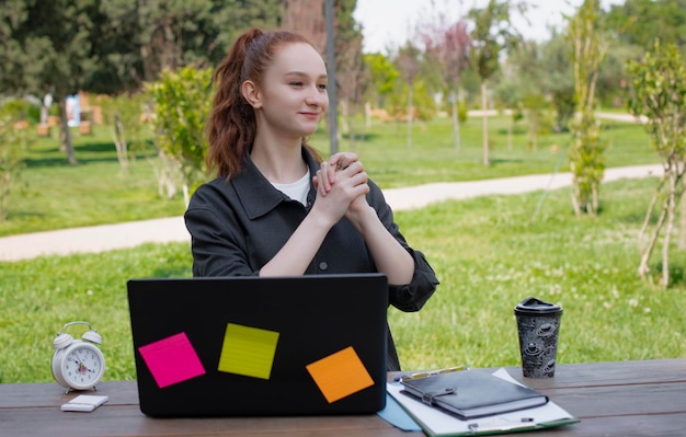 Pretty girl working at laptop in aprk hands in lock