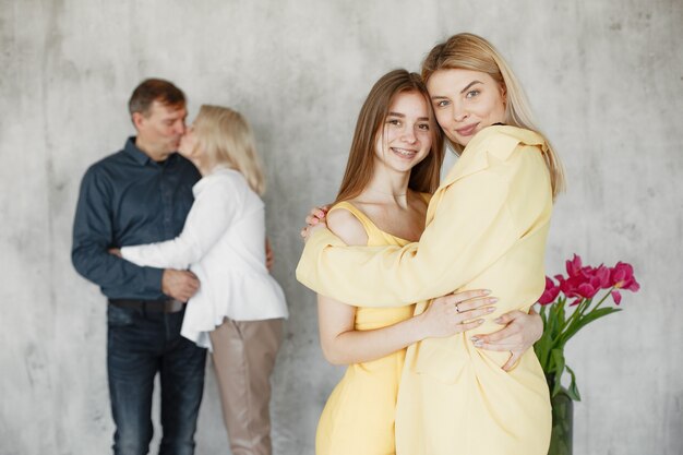 Pretty girls embracing and parents hugging blurred behind. 