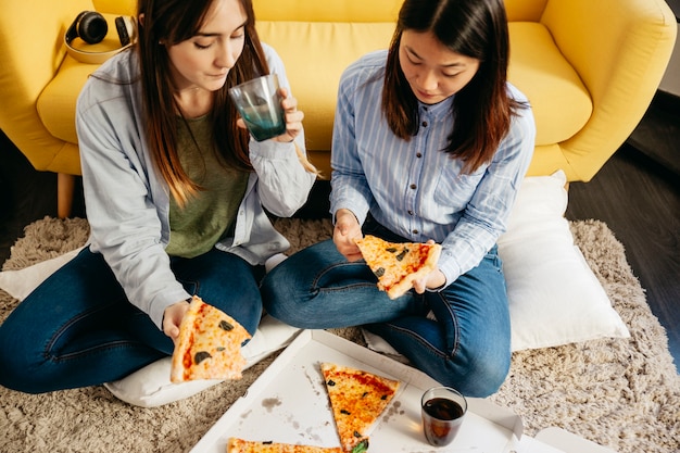 Free photo pretty girls having pizza on floor