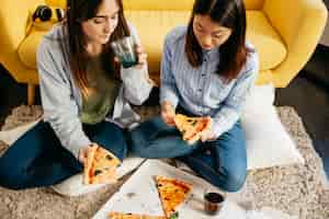 Free photo pretty girls having pizza on floor