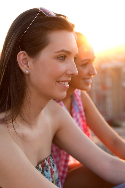 Pretty girls sitting on the roof at sunset.