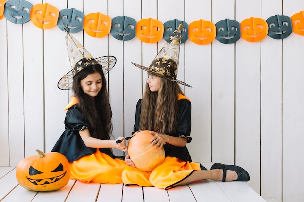 Free Photo pretty halloween witches decorating pumpkin