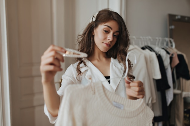 Free photo pretty lady holding white hair pin and beige sweater