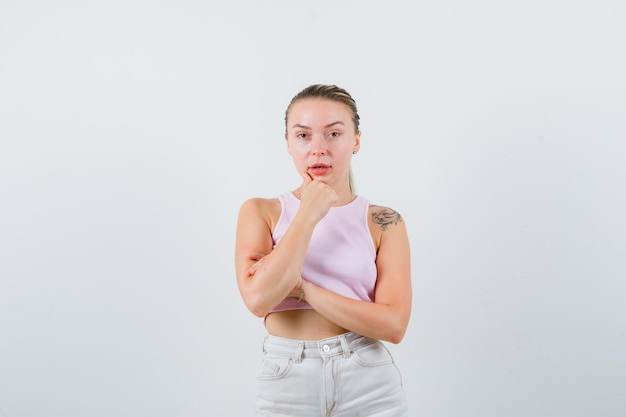 Pretty lady is putting her finger under her chin on white background