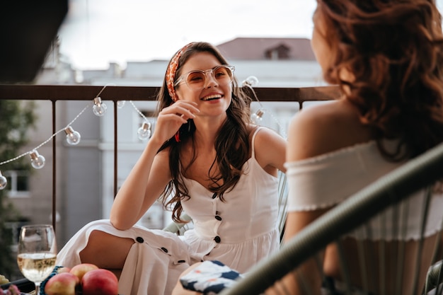 Pretty lady in white dress talks to her friend