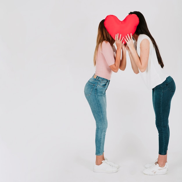 Pretty lesbian couple kissing behind heart