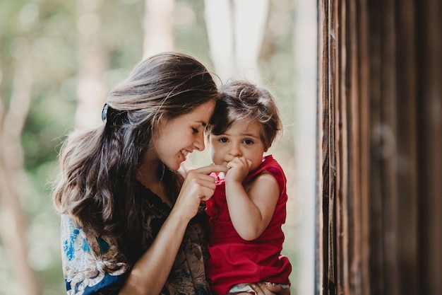 Pretty little child holds mother's finger sitting on her arms