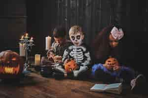 Free photo pretty little kids in halloween costumes are enjoying party while reading book.