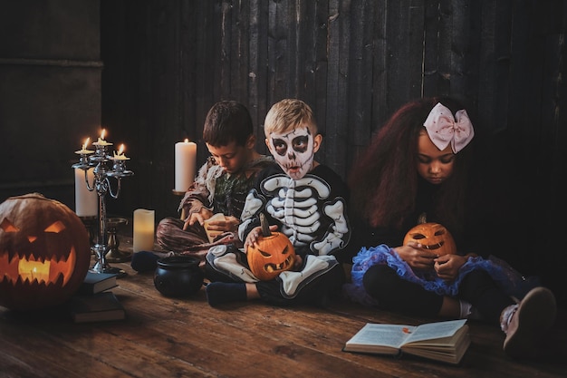 Pretty little kids in Halloween costumes are enjoying party while reading book.