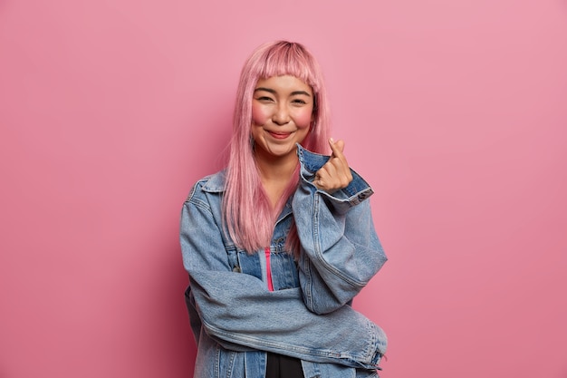 Free Photo pretty romantic asian woman with love cute smile, long pink hair, makes korean heart finger sign, expresses love and sympathy, confession