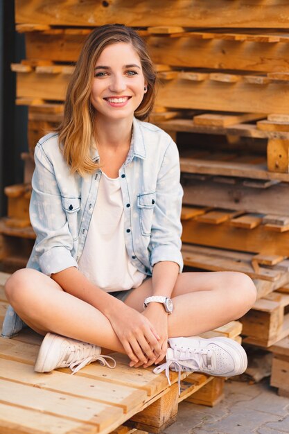 Pretty smiling girl, wearing jeans, shorts and shirt posing