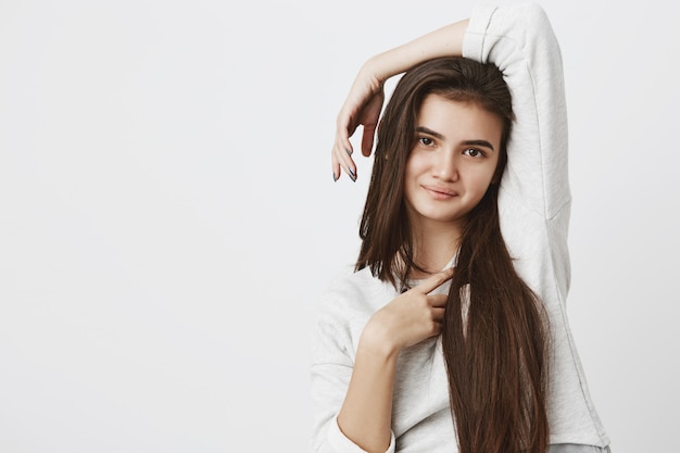 Free photo pretty smiling joyfully teenage woman with dark long hair, posing indoors, dressed casually.