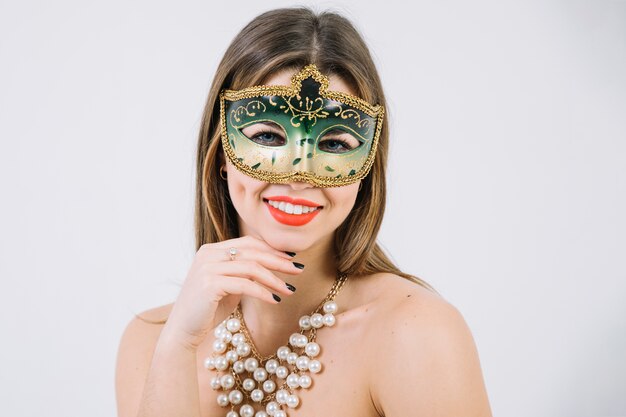 Pretty smiling woman wearing green decorative carnival mask