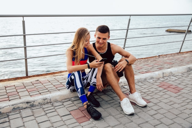 Pretty sportswoman and handsome sportsman watching a funny video on mobile phone