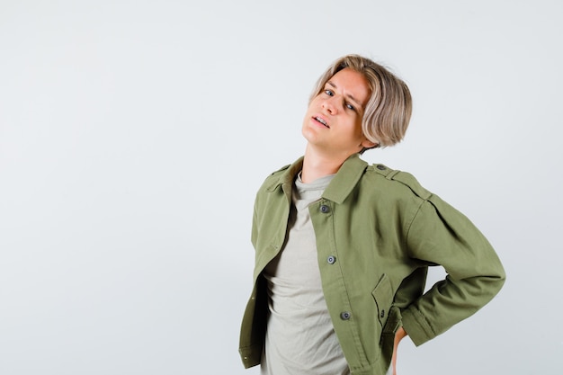 Free photo pretty teen boy suffering from backache in green jacket and looking exhausted