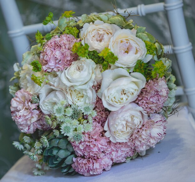 Pretty wedding bouquet of white and pink flowers standing on a white chair