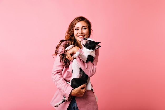 Pretty white girl holding bulldog and laughing. Blithesome caucasian woman with dog having fun.