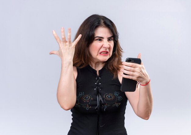 Pretty woman in black blouse angry looking at the phone doing up her arm 