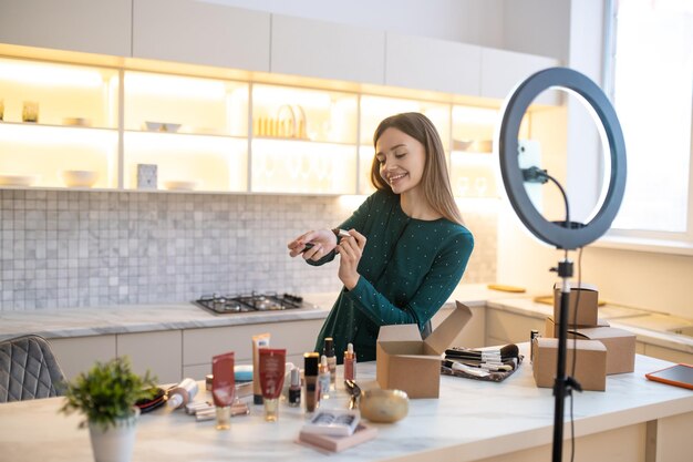 Pretty woman demonstrating new cosmetics and looking involved