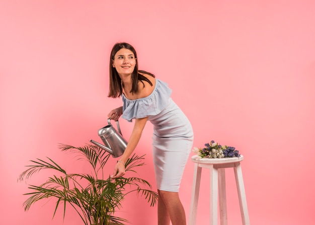 Pretty woman in dress watering green plant 