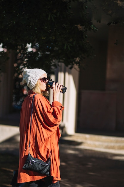 Free photo pretty woman drinking from thermos on street