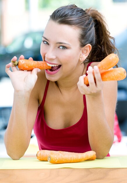 pretty woman eating carrots at home