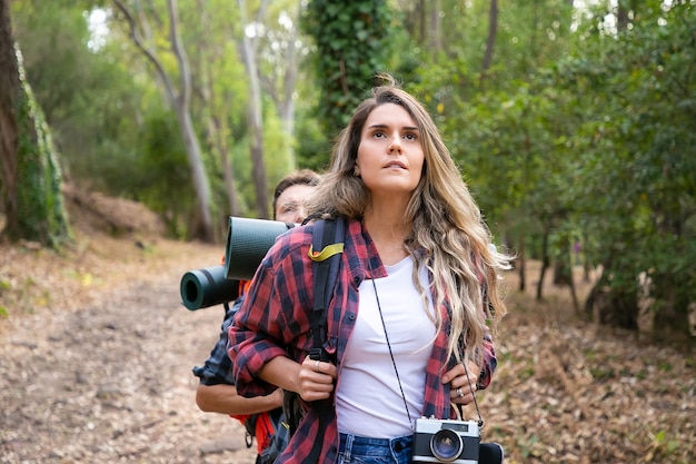 Free Photo pretty woman enjoying view and hiking. couple tourists walking in forest together. young caucasian hikers or traveler with backpacks trekking together. tourism, adventure and summer vacation concept