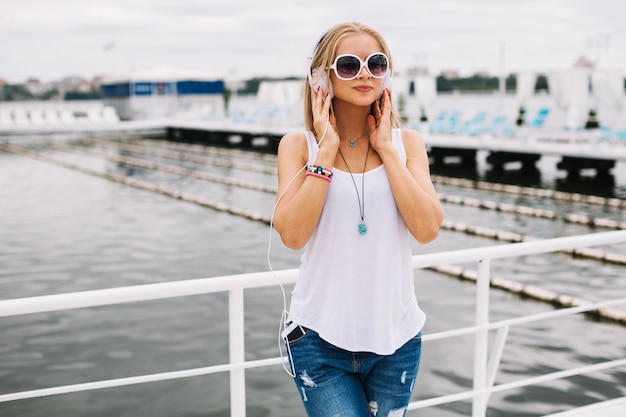 Free photo pretty woman listening to music on pier