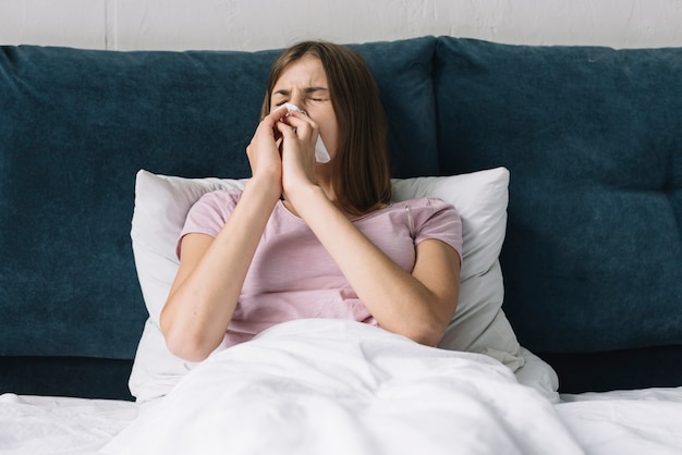 Free photo pretty woman lying on bed suffering from cold