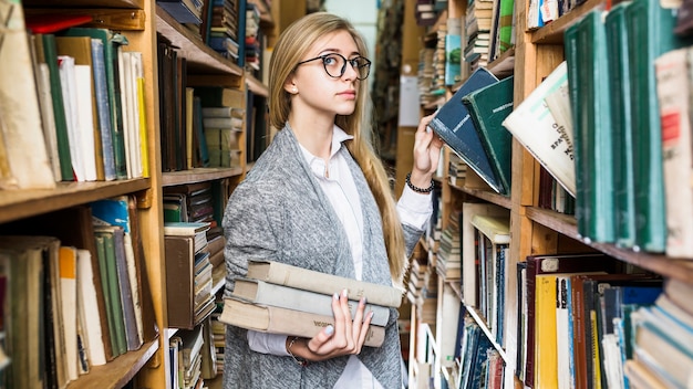 Free Photo pretty woman picking books in library