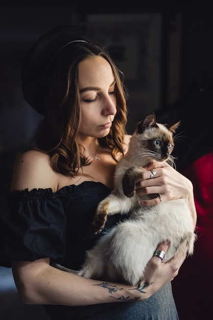 Free Photo pretty woman playing with siamese cat