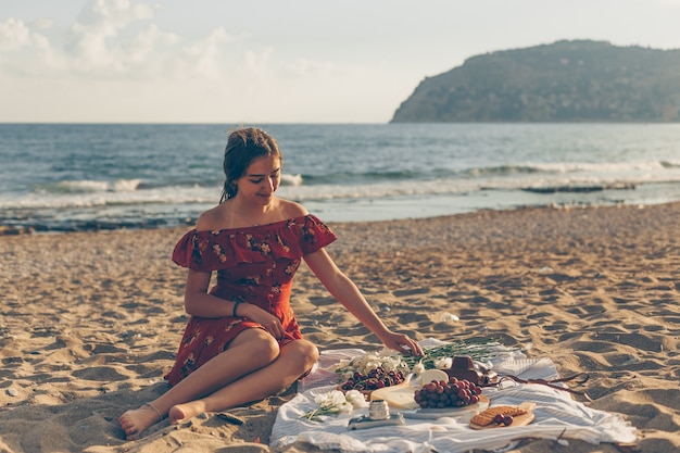 Pretty woman in red dress sitting on the beach during daytime