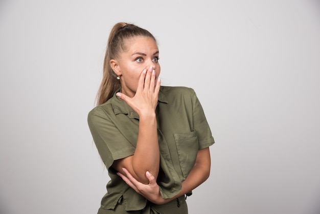 Pretty woman shocked about something on gray wall.