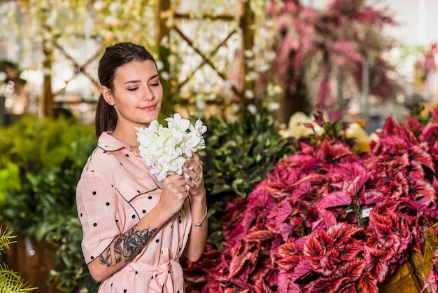 Free photo pretty woman smelling white flowers in green house