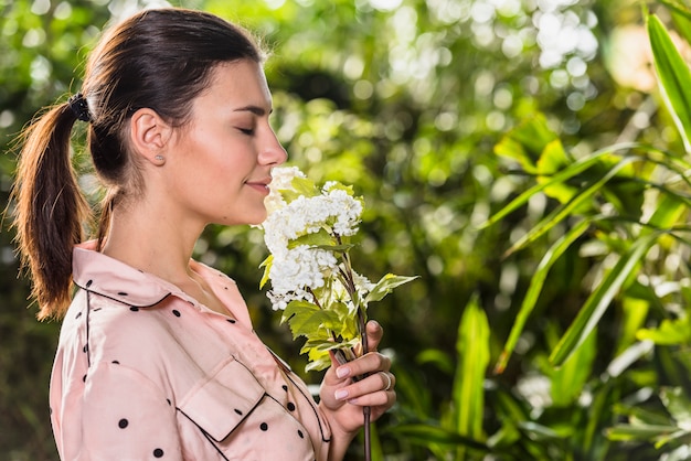 Free photo pretty woman smelling white flowers