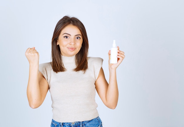 Pretty woman standing and posing with a spray on white background.