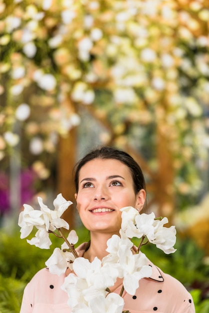 Free photo pretty woman standing with white flowers