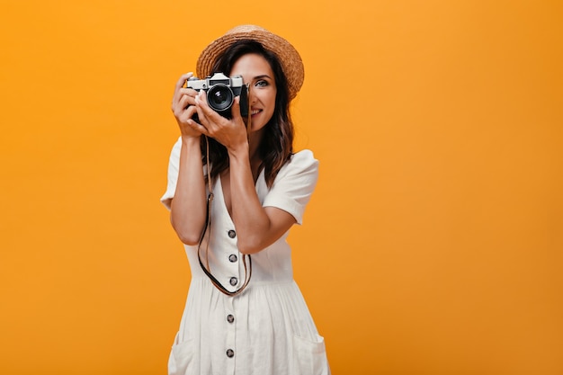 Pretty woman in straw hat holding retro camera on isolated background