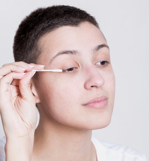 Pretty woman using a cotton bud to clean her make-up