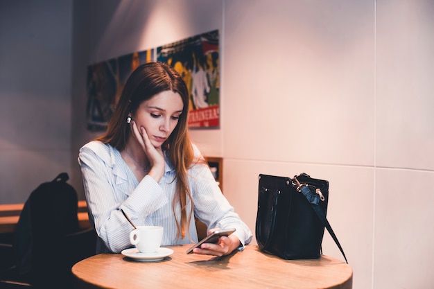 Free photo pretty woman using smartphone in cafe