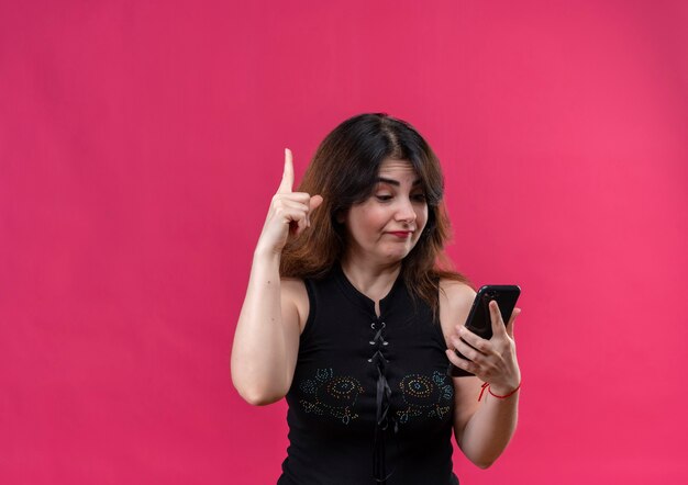 Pretty woman wearing black blouse points up looking on telephone