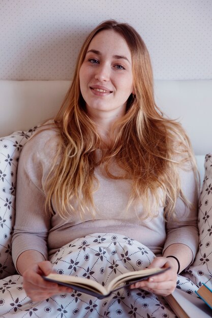 Pretty woman with book in bed