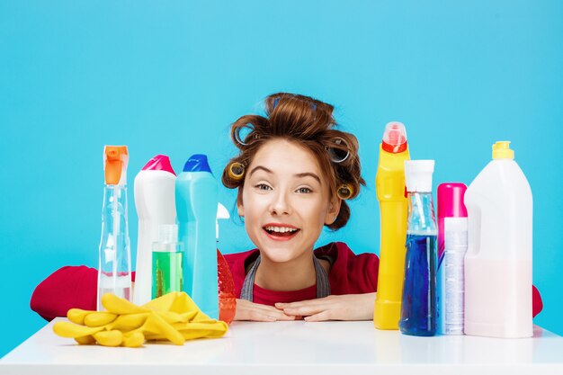 Pretty woman with cleaning tools smiles and looks pleased