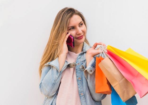 Pretty woman with colourful shopping bags talking by phone