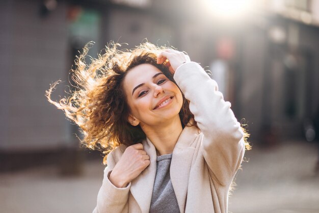 Pretty woman with curly hair walking in an autumn coat