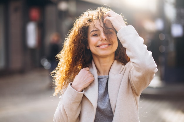 Pretty woman with curly hair walking in an autumn coat