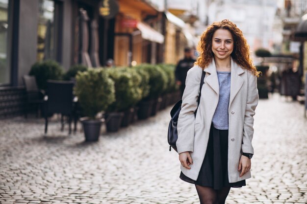 Pretty woman with curly hair walking at a cafe street