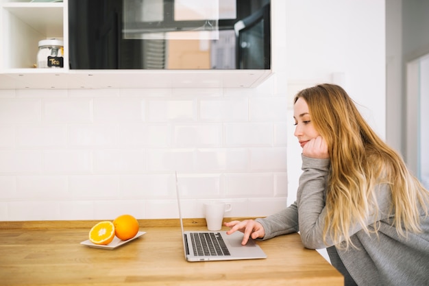 Free photo pretty woman with laptop in kitchen